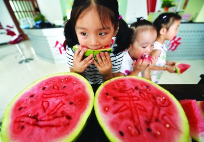 昨天︐康乐社区举办﹃啃秋﹄活动︐小朋友们用西瓜刻出﹃立秋﹄字样︒董辉贾春摄